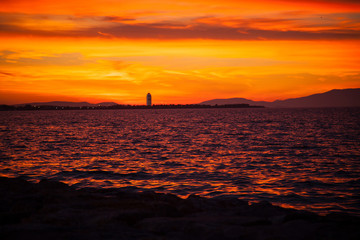 Fototapeta na wymiar A full sun setting over the sea, reflecting in the water