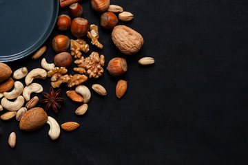 Different kinds on nuts and spices. Natural organic products for healthy lifestyle. Vegetarian food concept.  Raw almond, cachou, walnut, hazelnut, pistachio. Black background, closeup. Copy space