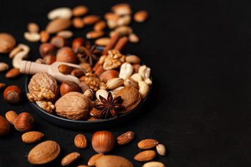 Different nuts and spices. Natural organic products for healthy lifestyle. Vegetarian food concept.  Raw almond, cachou, walnut, hazelnut, pistachio. Black background, closeup, copy space for text