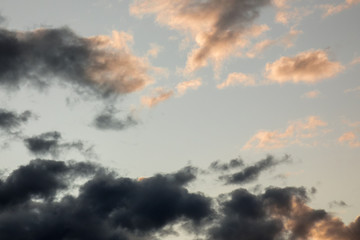 Blue sky with dark and orange early evening clouds.