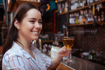Close up of a happy young woman having a drink at cocktail bar, copy space