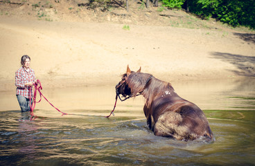 portrait of girl kissing red trakehner stallion horse in the river in the summer