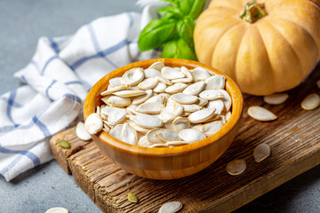 Unpeeled pumpkin seeds in a wooden bowl.