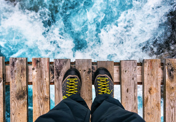 feet in boots on the edge of an old wooden bridge