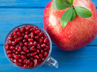 Pomegranate seeds in  transparent glass cup and one fruit close up. Nutrient, ripe.