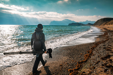 photographer with professional camera walks on the beach