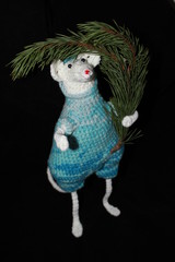 Knitted toy rat on a black background with a branch