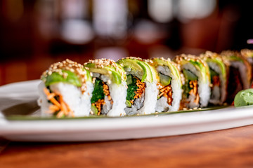 Vegan Meatless Avocado Carrot Cucumber Sesame Sushi Roll on a White Plate © Zachary