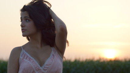 Beautiful woman standing staring at the camera at sunset