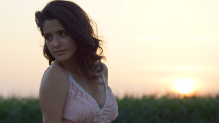 Beautiful woman standing staring at the camera at sunset