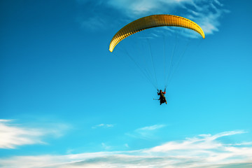 yellow paraglider flying in the sky