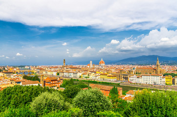 Obraz premium Top aerial panoramic view of Florence city with Duomo Santa Maria del Fiore cathedral, Ponte Vecchio bridge, buildings with orange red tiled roofs, Arno river, blue sky white clouds, Tuscany, Italy