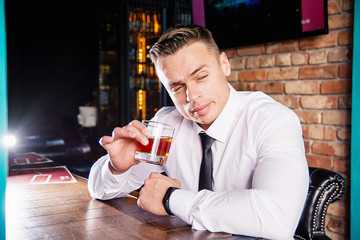 Businessman drinks whiskey at the bar