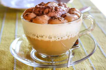 A cup of chocolate cappuccino with coffee, milk and ice cream and chocolate on top in a grass cup...