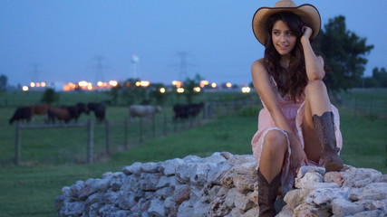 Beautiful woman sitting on a fence of rocks staring off into the camera