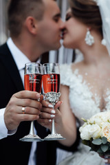 Bride and groom with champagne glasses. Wedding couple. The bride and groom kissing. Newlyweds clinking glasses and enjoying romantic moment together