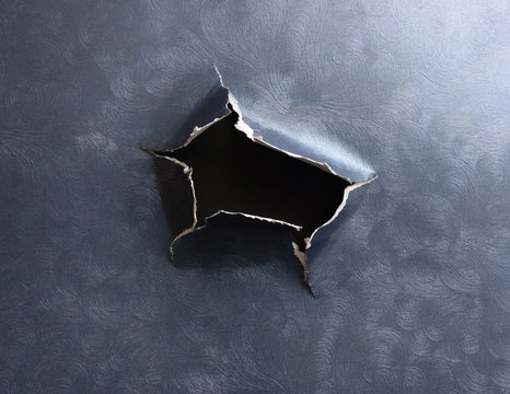 Hole torn in textured blue ripped paper