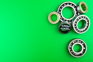 Ball bearing lying on a green background with copy space on the left side. Flat view from above.