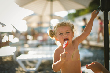 child on the beach with candy on a stick