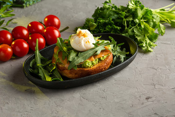 bruschetta salmon with avocado - salted salmon with guacamole, arugula and poached egg on a warm fried bun