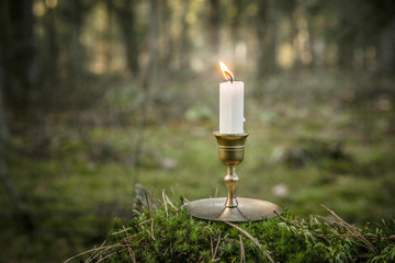 Single candle burning in forest. Burning candle in vintage candlestick outdoor.  .