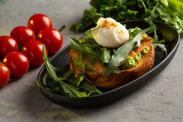 bruschetta salmon with avocado - salted salmon with guacamole, arugula and poached egg on a warm fried bun