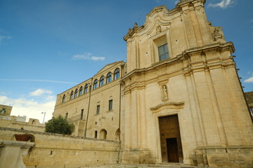 Obraz premium Church and Convent of Sant'Agostino in Matera. Courtyard with olive trees with leaves moving in the wind..