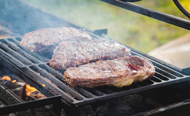 steak with sausages and wurstel on the fire of the barbeque with charcoal glowing incandescent