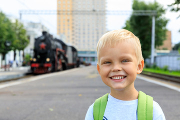 little boy tourist meets Old black steam locomotive in Russia on the background of the Moscow railway station