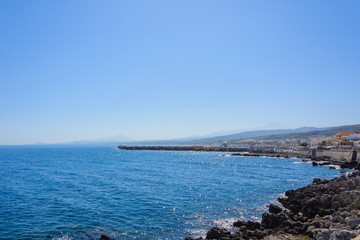 a small Bay with a breakwater built of stones. the city on the shore. silhouettes of mountains on the horizon.