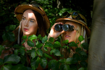 Two young girls dress up as explorers. They wears safari hats and wears khaki clothing. They are...