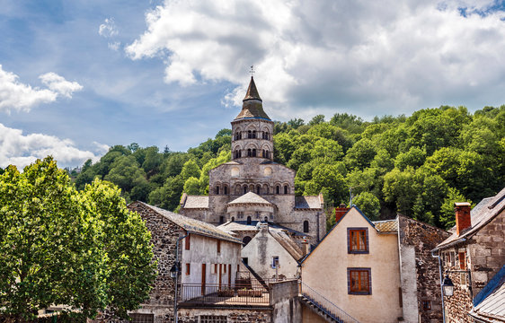 Basilica Notre Dame d&rsquo;Orcival seen from the village. Parts of old houses are at foreground. Puy-de-Dome department in French Auvergne.