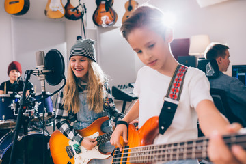 kids rock band playing instruments in music studio