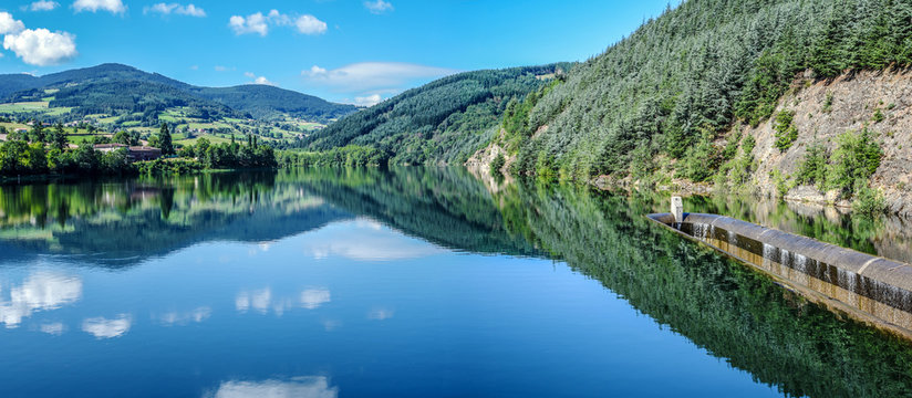 Dorlay Reservoir Collecting Water From Dorlay River In French Auvergne-Rhone-Alpes Region.  The Part Od The Barrage Concrete Construction Is At Right. Hills Of Pilat Massif Is At Background.