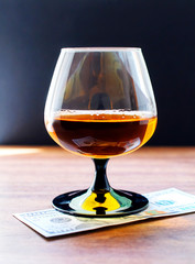  Cognac in a glass on a wooden table with a dollar bill