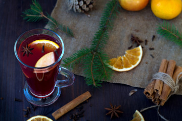 mulled wine with slices of orange, apple and spices, cinnamon and anise star on a wooden table with...
