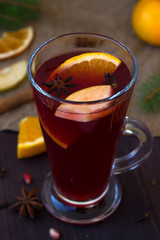 glass of mulled wine with slices of orange, apple and spices, cinnamon and anise star on a wooden background with winter decorations. top view. hot drinks of winter and autumn. vertical