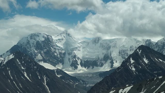 White snowy peaks of the mountain range under the clouds. The highest point of the Altai Mountains, Mount Belukha. 4k footage.
