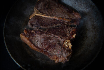 Delicious Simply Cooked T-bone steak on Stainless Steel Skillet