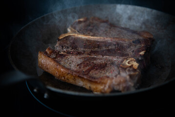 Delicious Simply Cooked T-bone steak on Stainless Steel Skillet