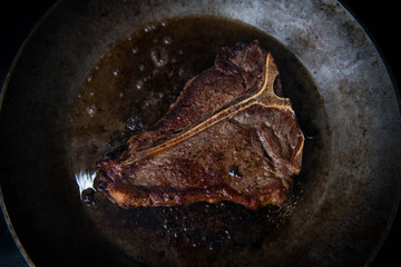 Delicious Simply Cooked T-bone steak on Stainless Steel Skillet