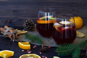 two glasses with hot mulled wine with orange, apple and spices on a wooden background with winter decorations. hot drinks of winter and autumn. autumn or winter still life.