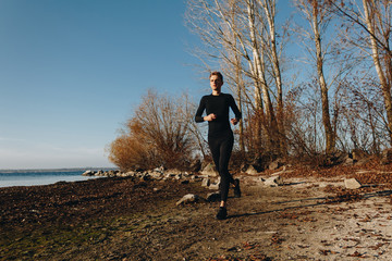 young man in sportswear running on the wild beach