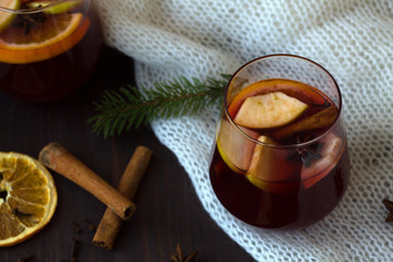winter still life. red mulled wine in a glass with orange, apple and cinnamon, anise star and warm...