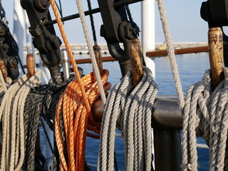 White, orange and black ropes dry on the rail on a sailing ship on a Sunny summer day. The rigging...