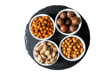 A variety of nuts in bowls on a stone board. Top view. Isolated over white background.