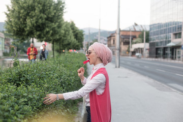 romantic portrait of young European Muslim woman with hijab have fun at beautiful sunny day. Image of pretty woman walking with red heart shaped lollipop. She is happy and relaxed.