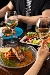 People are eating stewed chum salmon with vegetables with a glass of white wine in a restaurant