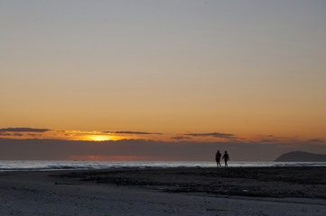 Fototapeta premium sunrise view and silhouette of couple walking on the beach