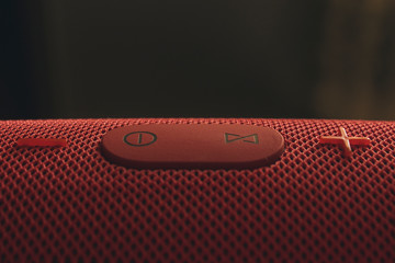 Wireless music speaker. Red Bluetooth speaker. Control and volume buttons.
